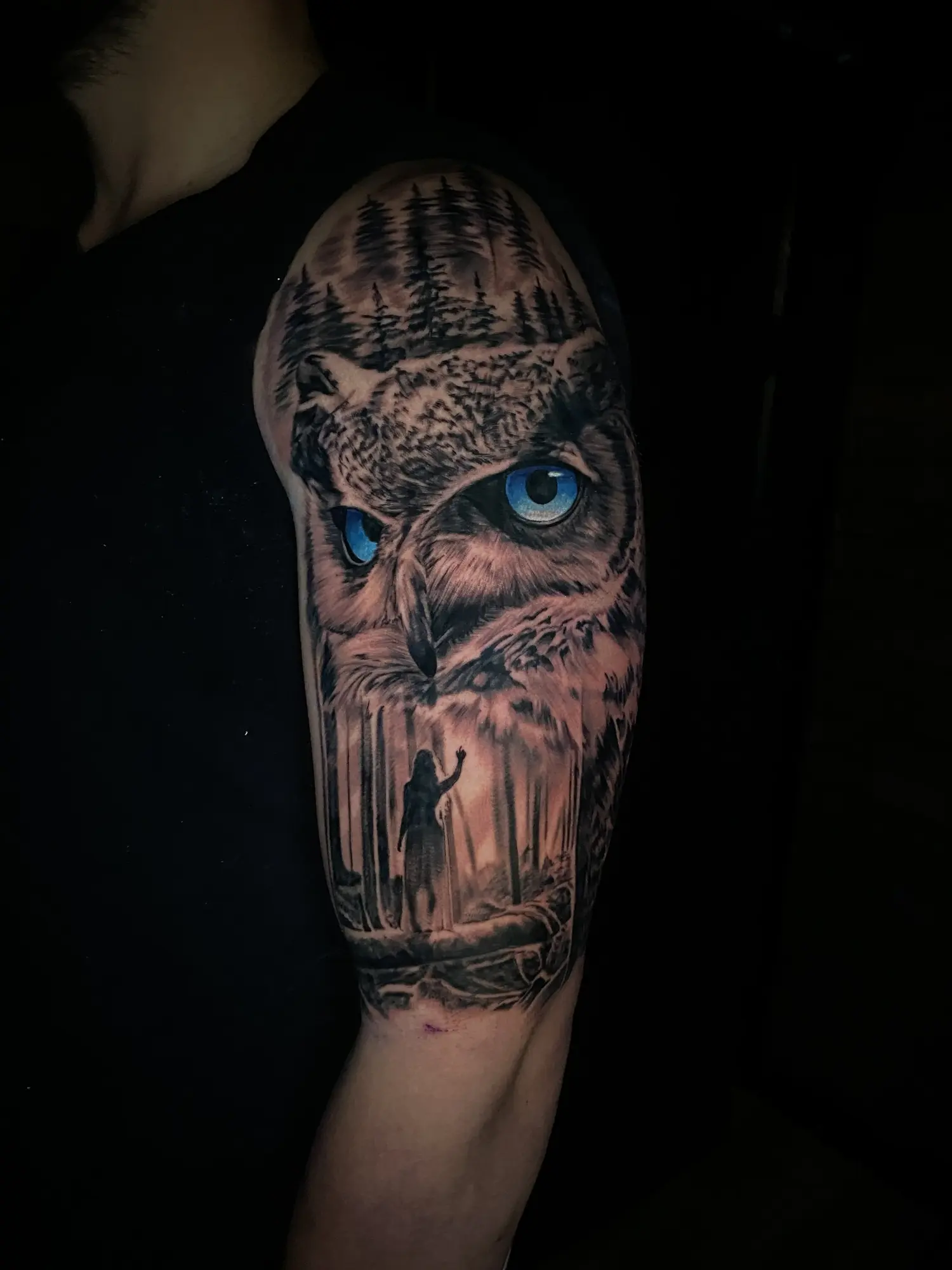 Color realism owl tattoo with a blue eye and candlelit forest