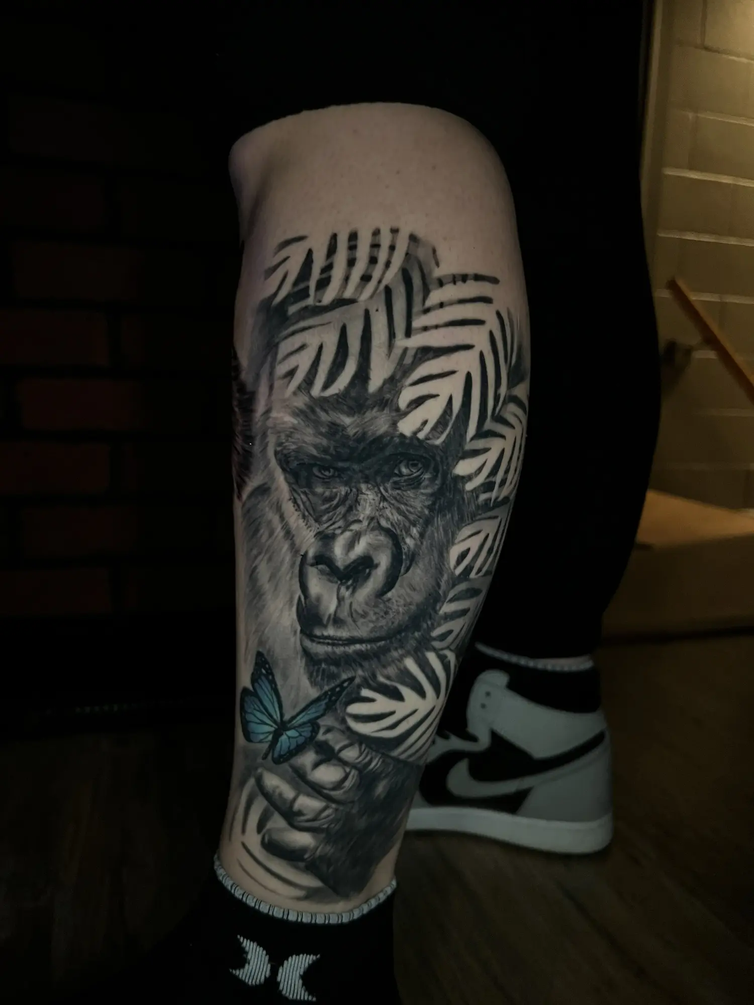Black and grey gorilla portrait tattoo with a blue butterfly accent