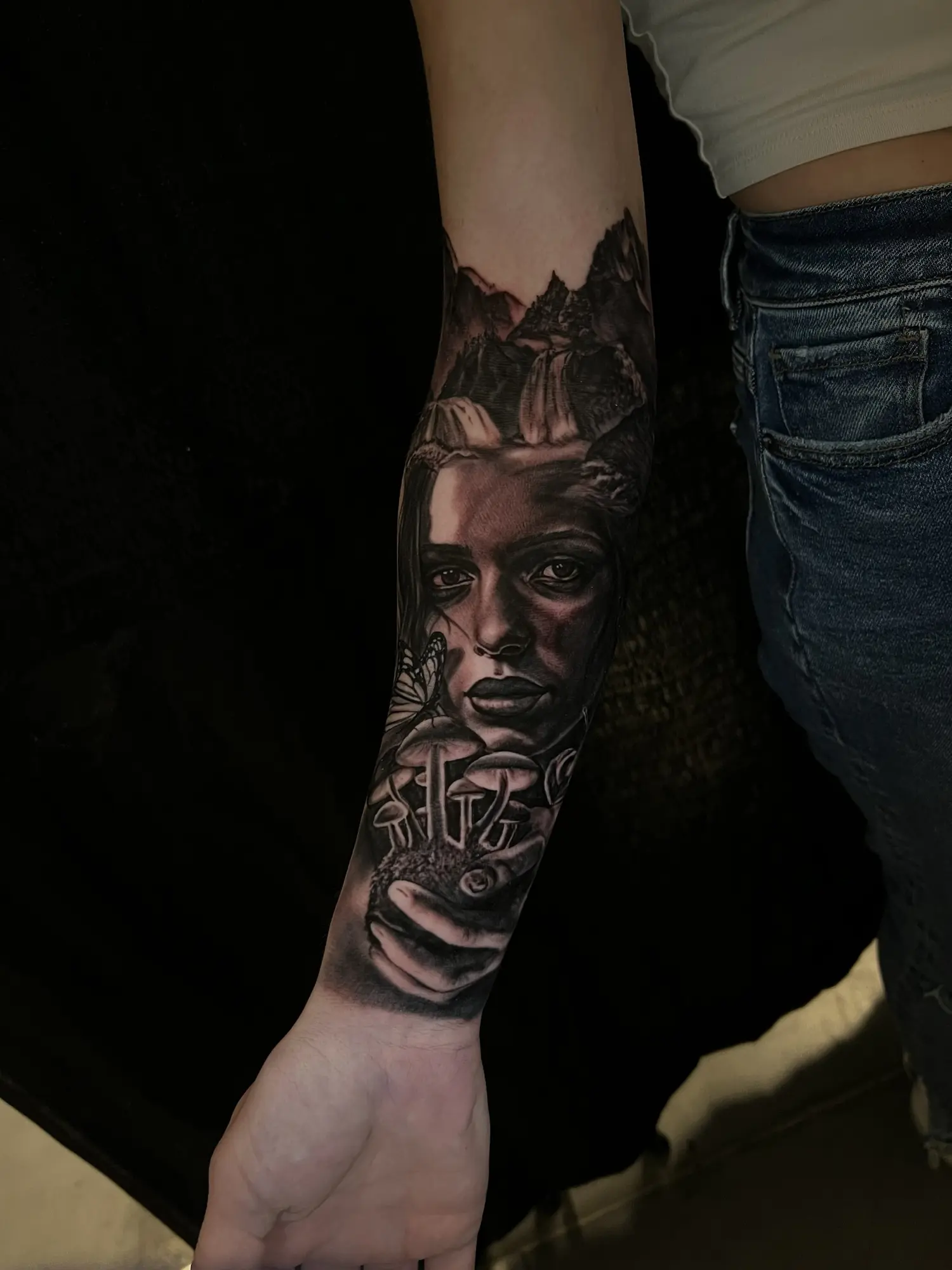 Black and grey illustrative female portrait and hand forearm tattoo