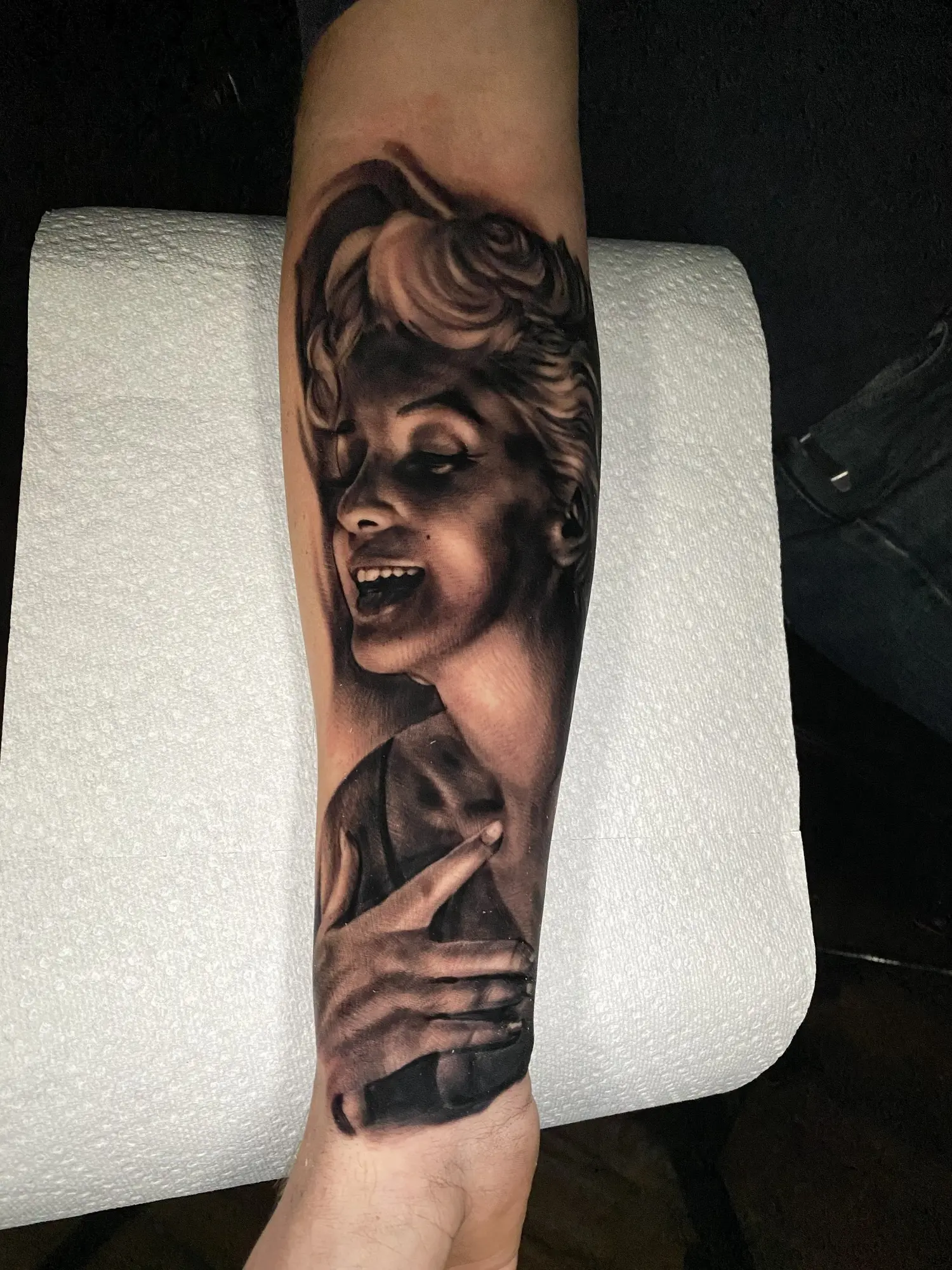 Black and grey female portrait, rose, and hand forearm tattoo